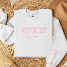 a white sweatshirt with the bride est 2013 printed on it next to straw hats and fan