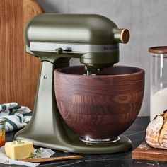 a green mixer sitting on top of a counter next to bread and cheese slices in front of it