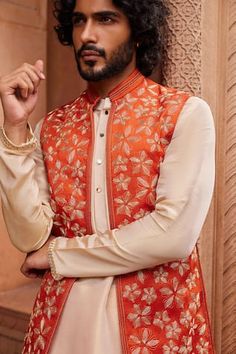 Rust orange bundi with dori embellishment in floral pattern. Paired with beige kurta and pant. - Aza Fashions Luxury Spring Festive Nehru Jacket, Luxury Cotton Silk Nehru Jacket For Diwali, Luxury Cotton Silk Nehru Jacket For Eid, Designer Sleeveless Kurta With Dori Work, Transitional Orange Zari Work Kurta, Traditional Sleeveless Kurta For Reception, Sleeveless Embroidered Bandhgala For Festive Season, Festive Sleeveless Nehru Jacket With Resham Embroidery, Festive Embroidered Sleeveless Bandhgala