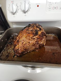 a roasting pan with a piece of meat in it on top of a stove