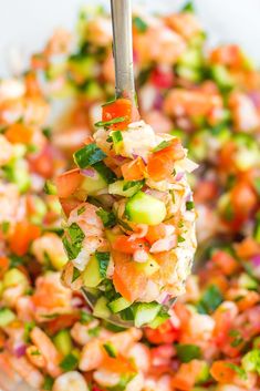 a spoon full of chopped vegetables being lifted from a bowl with the salad in it