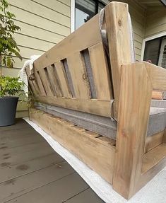 a wooden bench sitting on top of a porch next to a potted green plant