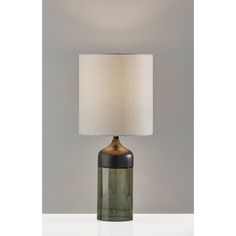 a green glass table lamp with a white linen shade on the top and bottom part