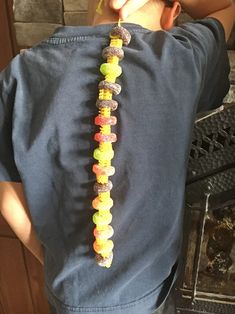 a young boy wearing a blue shirt with candy beads on it's back and his hands behind his head