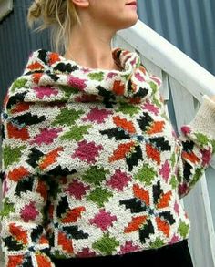 a woman standing on the steps wearing a colorful sweater