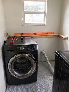 a washer and dryer in a small room next to a window with no curtains