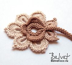 a crocheted flower is shown on a white surface