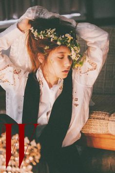 a woman sitting on top of a couch next to a flowered headband and wearing a white shirt