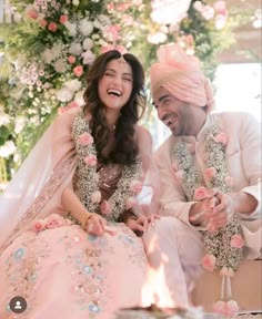 a man and woman sitting next to each other in front of a flower covered wall