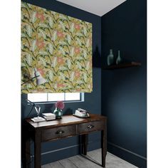 a room with blue walls and a floral roman blind in front of a desk area