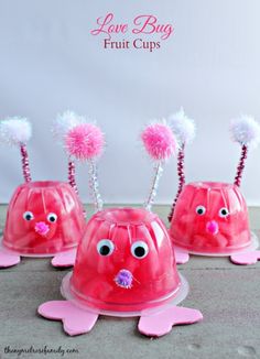 three pink plastic cups with googly eyes and pom - poms on them