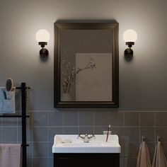 a bathroom sink sitting under a mirror next to a towel dispenser and two lights