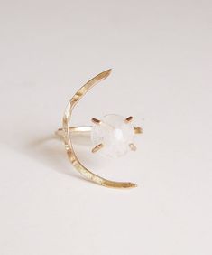 This beautiful white moonstone gemstone features a subtle glow. Set in 14k gold fill, this ring is a perfect for everyday wear or as a statement piece.Featuring a stunning crescent moon shape design.Ring is made in size 6 and is adjustable due to the style of the ring.It can be made larger upon request before purchase.Gemstone is approx. 10mm in diameter.This piece is a very limited edition.Please note: Due to the nature of the moonstones, each of these stones can vary from the original.My QUALI Moonstone Crystal Ring With Moon Phase, Adjustable Gold Moon-shaped Moonstone Ring, White Adjustable Celestial Moonstone Ring, Adjustable Ethereal Moonstone Ring, Ethereal Adjustable Moonstone Ring, Moonstone Open Ring With Moon Phase Detail, Adjustable Crescent Moonstone Ring, Minimalist Moonstone Moon-shaped Ring, Adjustable Moon Shaped Elegant Crystal Ring