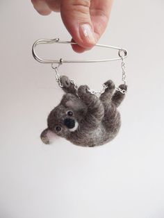 a hand holding a keychain with a stuffed animal hanging from it