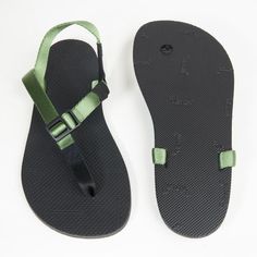 a pair of black and green flip flops on a white surface, with straps