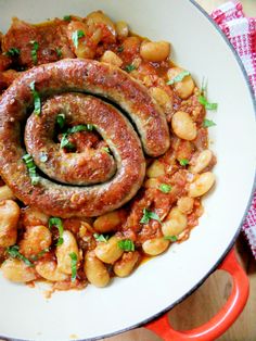 two sausages and beans in a skillet with garnish on the side