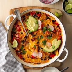 a casserole dish with tortilla and avocado on the side