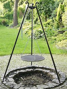 a metal swing with chains hanging from it's sides in the middle of a garden