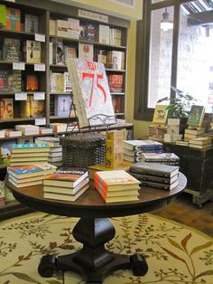 there is a table with books on it in the room and many other books are sitting on the shelves