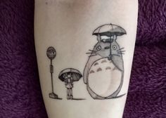 a person with a tattoo on their leg has a totoro holding an umbrella