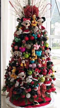 a christmas tree decorated with mickey mouses and other holiday decorations is shown in front of a window