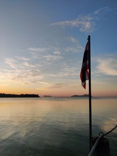 a flag on the side of a boat at sunset