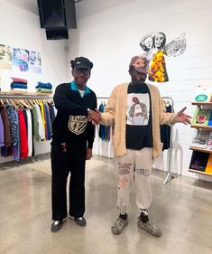 two people standing next to each other in front of shirts on hangers and shelves