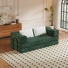 a green couch sitting on top of a wooden floor next to a white and black rug