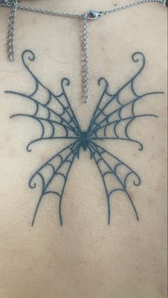 a spider web tattoo on the back of a man's chest, with chains attached to it