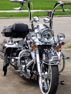 the motorcycle is parked on the side of the road in front of some green grass