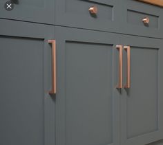 a kitchen with gray cabinets and copper pulls on the doors, along with white walls