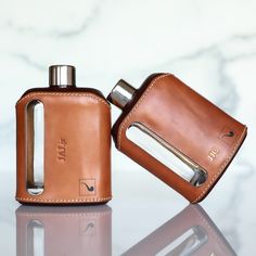 two leather flasks sitting next to each other