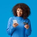 a woman in a blue sweater is looking at her cell phone and holding a smart phone