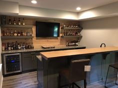 a bar with two stools in front of it and a television mounted on the wall