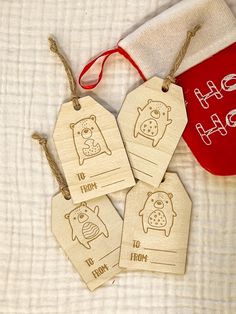 four wooden tags with animals on them sitting next to a christmas stocking hanging from a red bag