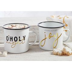 two coffee mugs sitting next to each other with marshmallows on the side