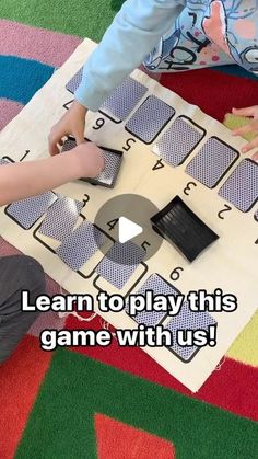 two children are playing with a game on the floor and one child is holding a cell phone