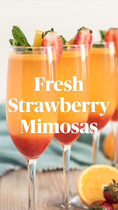 three glasses filled with orange juice and garnished with strawberries on the rim