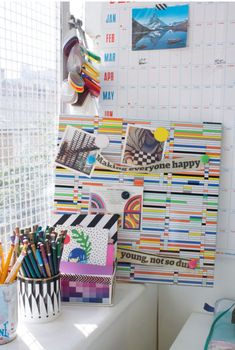 a desk with many different colored pencils and markers on it next to a calendar