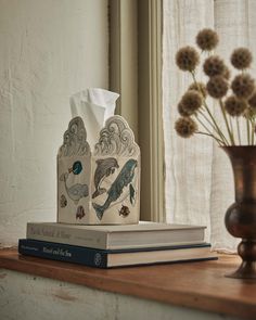 two books are sitting on a shelf next to a vase with some flowers in it