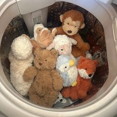 several stuffed animals are sitting in the front of a dryer basket on top of a washing machine