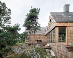 the house is made out of wood and has large windows on each side, along with stone steps leading up to it