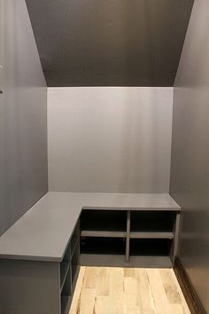 an empty room with some shelves and a bench in the corner on top of a hard wood floor