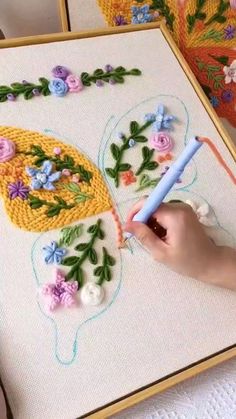 a person is working on a cross - stitch project with flowers and a peacock motif