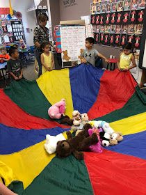 children are playing with a large parachute in the middle of a room filled with stuffed animals