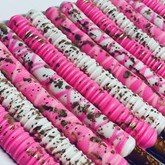 pink and white candy sticks are lined up on a table with sprinkles