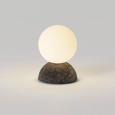 a white light sitting on top of a rock next to a gray wall and floor