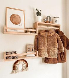 two wooden shelves holding books, toys and other items on top of them in front of a white wall