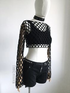 a white mannequin wearing a black top with holes on it's chest