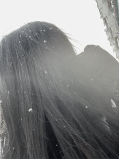 the back of a woman's head with her hair blowing in the wind and snow